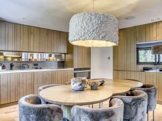 This stunning kitchen boasts a modern design with sleek wooden cabinetry and a unique, eye-catching light fixture.