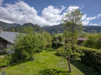 This stunning property boasts a lush green lawn and mature trees, creating a serene outdoor space.
