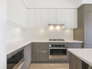 This modern kitchen boasts sleek, white cabinetry that contrasts beautifully with the warm, wood-toned lower cabinets.