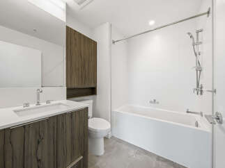 This modern bathroom boasts a sleek design with a pristine white bathtub and shower area.