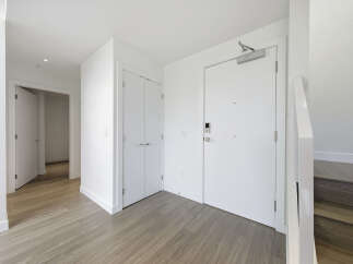 Step into a bright and modern entryway, featuring sleek white doors and walls that create a spacious feel.