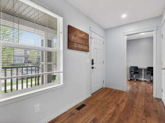 Step into this inviting entryway, featuring beautiful hardwood floors and a welcoming 'Welcome to Our Home' sign.