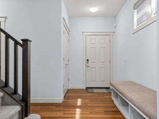 Step into this inviting entryway, featuring a stylish staircase and a welcoming bench.