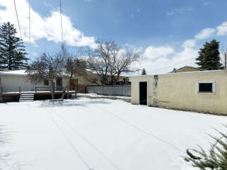 This charming property boasts a spacious backyard blanketed in pristine snow, perfect for winter activities.