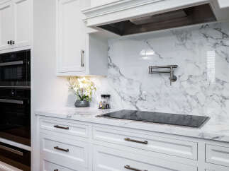 This stunning kitchen boasts a sleek, modern design with pristine white cabinetry and elegant marble countertops.