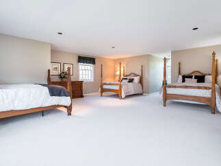 Step into luxury with this expansive bedroom, boasting three elegant four-poster beds.