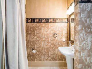 Step into a unique bathroom retreat! This space features a distinctive wallpaper design, adding a touch of vintage charm.