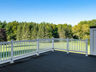 Enjoy breathtaking views from this stunning property! This home features a spacious deck with a white railing, perfect for relaxing and entertaining.