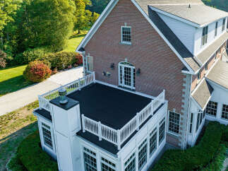 This stunning brick home boasts a charming exterior with a flat roof and a white railing.