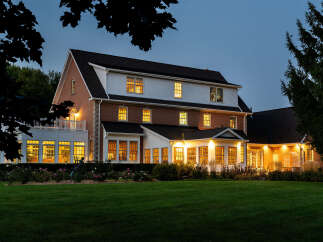 This stunning property showcases a beautifully lit, multi-story home with a classic brick facade and a welcoming, well-manicured lawn.