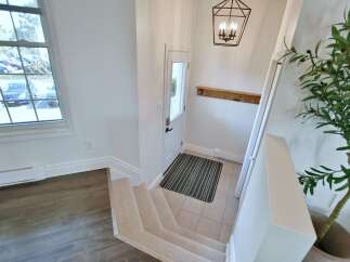 Step into this inviting entryway, featuring a stylish staircase and a welcoming front door.