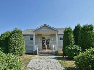 This charming property features a welcoming facade with a covered porch and a well-maintained gravel pathway leading to the front door.