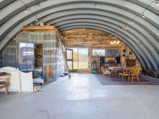 Discover this unique Quonset hut home, offering an expansive open-concept living space with rustic charm.