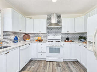 This stunning kitchen boasts a modern design with sleek white cabinetry and a stylish backsplash.