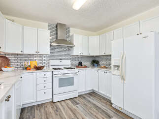 Step into this bright and inviting kitchen, featuring pristine white cabinetry and a stylish brick backsplash.