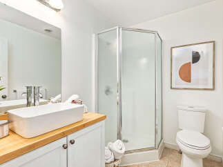 Step into this modern bathroom, featuring a sleek glass shower and a stylish vessel sink.