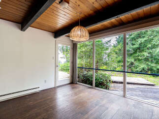 This stunning property boasts a bright and airy interior with a beautiful wooden ceiling and large windows that offer breathtaking views of the lush greenery outside.