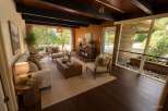 Experience mid-century modern living in this stunning home featuring a wood-paneled living room with a beamed ceiling and large windows that bring the outdoors in.