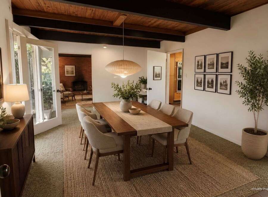 Experience elegant dining in this beautifully staged room, featuring a warm wood dining table set on a natural fiber rug.