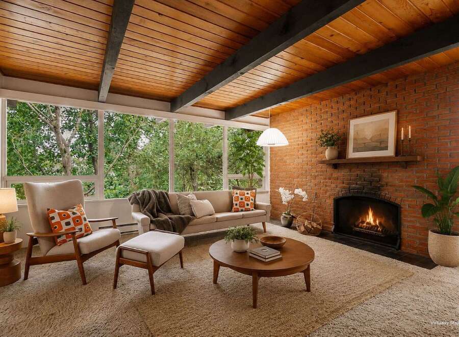 Experience mid-century modern charm in this inviting living room, featuring a stunning wood-paneled beamed ceiling and a cozy brick fireplace.