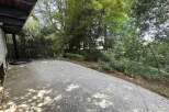 Enjoy the lush greenery surrounding this property, featuring a spacious concrete patio perfect for outdoor entertaining.