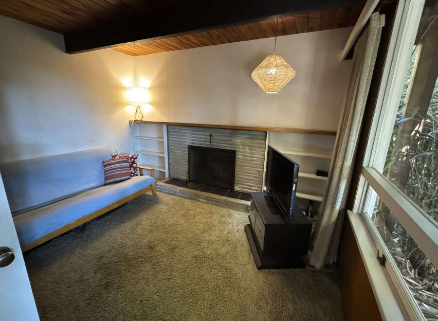 Cozy living room featuring a comfortable futon, a stone fireplace, and built-in shelving.