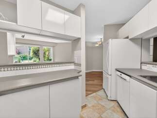 Step into this bright and airy kitchen, featuring sleek white cabinetry and ample counter space.
