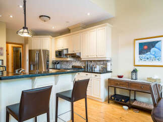 This stunning kitchen boasts elegant white cabinetry, a sleek black countertop, and modern stainless steel appliances.