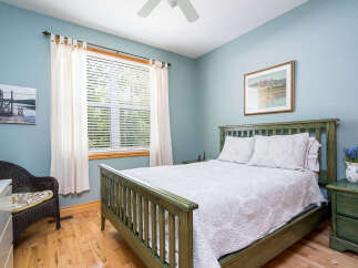 This charming bedroom offers a serene retreat with its calming blue walls and natural light.
