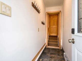 Step into this inviting entryway, featuring a charming coat rack and a warm, wooden door leading to the interior.
