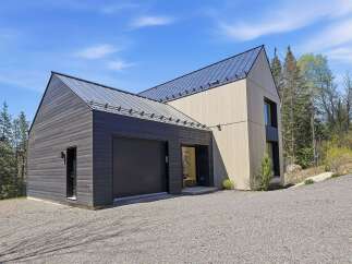 This modern home boasts a striking architectural design with a sleek, dark exterior and a contrasting light-colored facade.