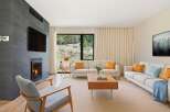 Experience modern living in this stunning living room, featuring a sleek fireplace with an integrated TV and a large window offering breathtaking natural views.