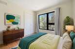 This bedroom offers a serene retreat with its large window overlooking a lush forest, bringing the outdoors in.