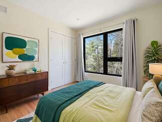 This bedroom offers a serene retreat with its large window overlooking a lush forest, bringing the outdoors in.