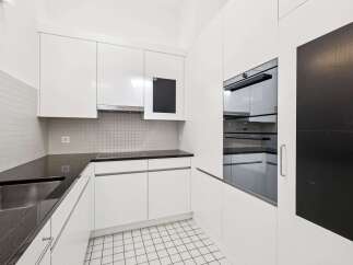 This modern kitchen boasts sleek white cabinetry and a contrasting black countertop, creating a stylish and functional space.