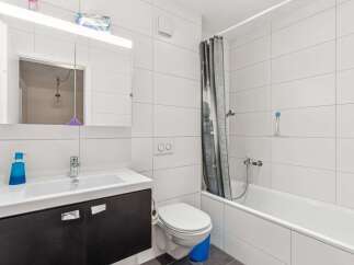 This modern bathroom features a sleek design with white tiled walls and a dark vanity.