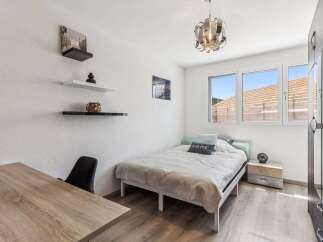 This cozy bedroom offers a serene retreat with its minimalist design and ample natural light.