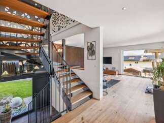 This stunning property boasts a modern design with a striking staircase as its centerpiece.