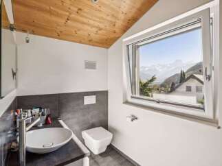 This modern bathroom boasts a stunning view of the mountains through a large window.