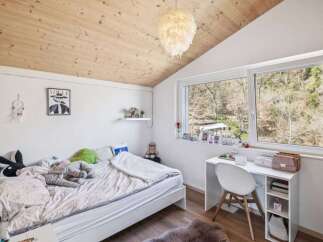 This cozy bedroom features a unique wooden ceiling and a large window offering scenic views.