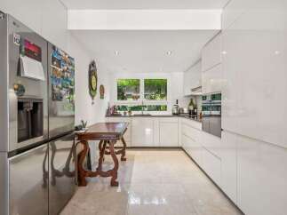 This modern kitchen boasts sleek white cabinetry and stainless steel appliances, creating a bright and airy atmosphere.