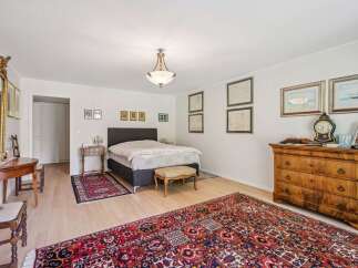 This elegant bedroom features a luxurious design with hardwood flooring and a large, ornate rug.