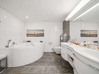 This luxurious bathroom features a modern design with a sleek, curved bathtub and vanity.