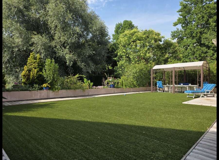Enjoy outdoor living in this beautifully landscaped backyard featuring a pristine artificial lawn perfect for recreation.