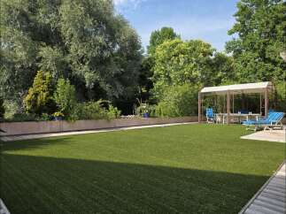 Enjoy outdoor living in this beautifully landscaped backyard featuring a pristine artificial lawn perfect for recreation.