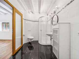 Step into this beautifully designed bathroom featuring a modern shower, sleek black tiled floors, and pristine white walls.