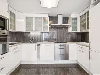 This modern kitchen boasts sleek white cabinetry and stainless steel appliances, creating a clean and contemporary aesthetic.