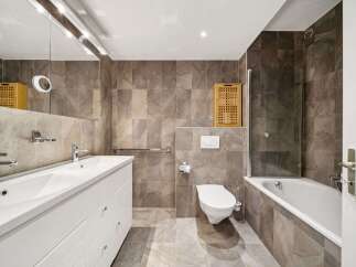 Step into a modern bathroom oasis! This stunning space features sleek white cabinetry, a double sink, and elegant tile work.