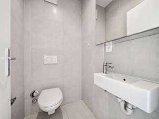 This modern bathroom features sleek, neutral-toned tiles and a minimalist design.