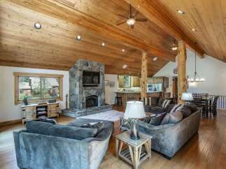 This stunning property boasts a cozy living room with a stone fireplace and a large TV, perfect for relaxing evenings.